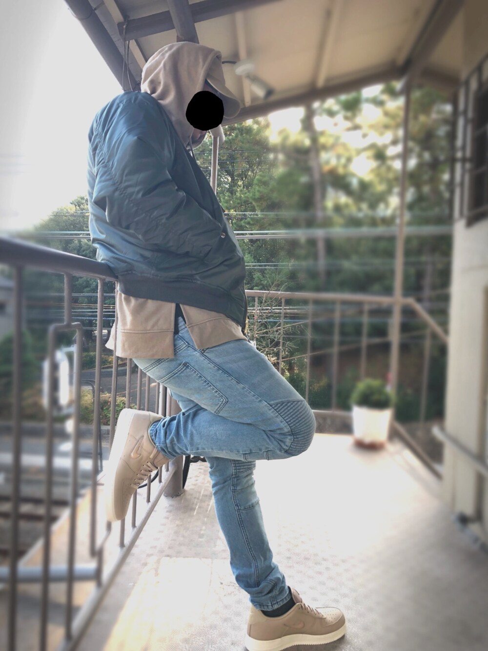 グリーン系のMA-1、ベージュ系のパーカー、ブルー系のデニムパンツを着用したメンズの冬コーディネートの1枚目の写真
