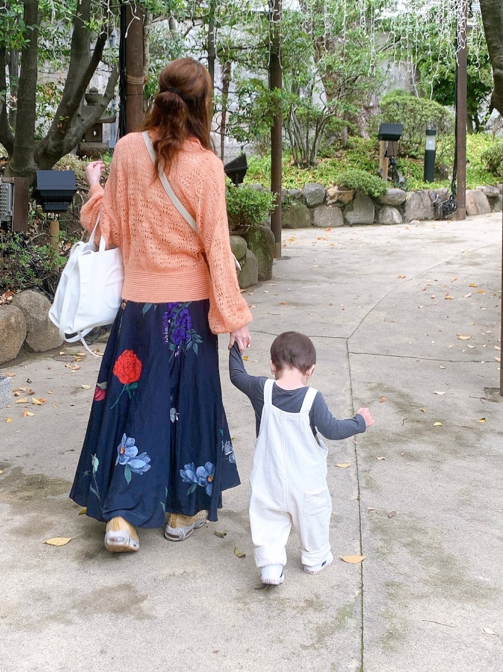 ブルー系のスカート、オレンジ系のニット/セーター、ホワイト系のトートバッグを着用したレディースの春コーディネートの1枚目の写真