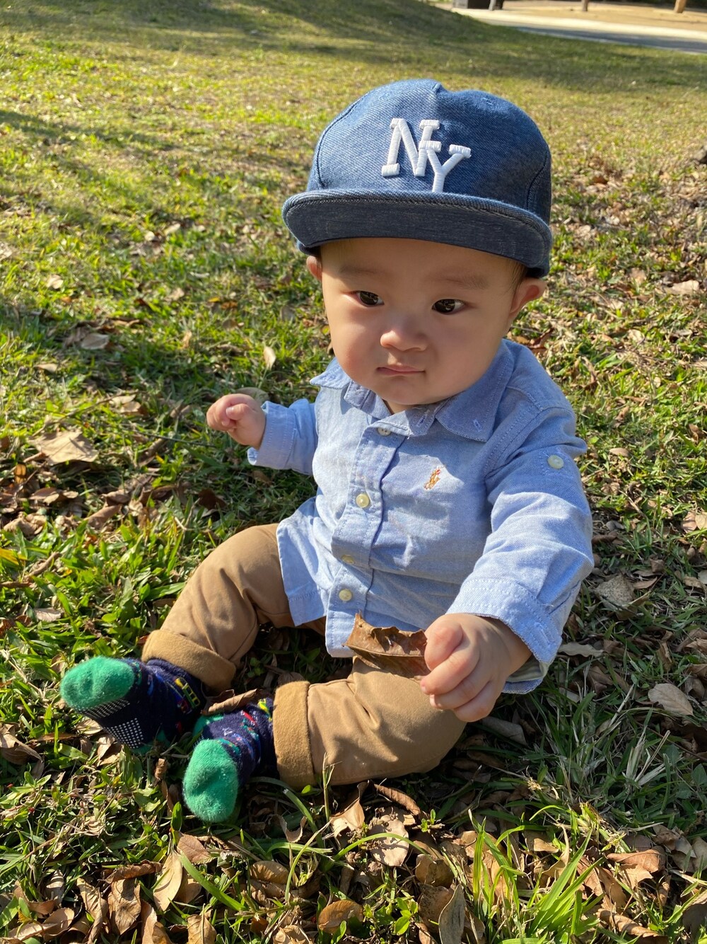 ブルー系のシャツ/ブラウス、オレンジ系のチノパンツ、ブルー系のキャップを着用したキッズの春コーディネートの1枚目の写真