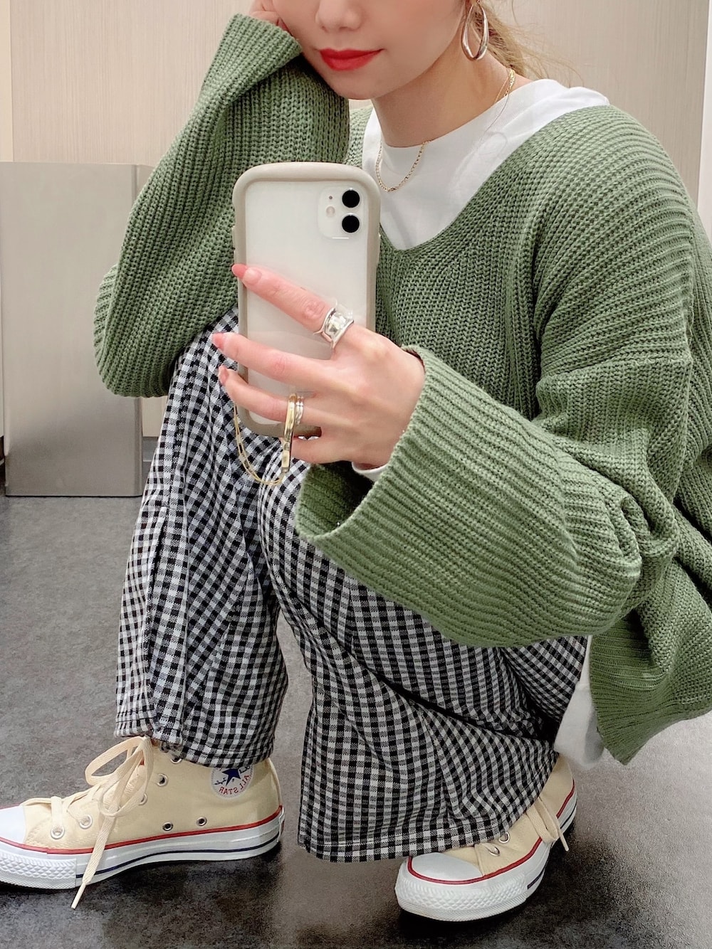 グリーン系のニット/セーター、ホワイト系のTシャツ/カットソー、ブラック系のパンツを着用したレディースの冬コーディネートの1枚目の写真