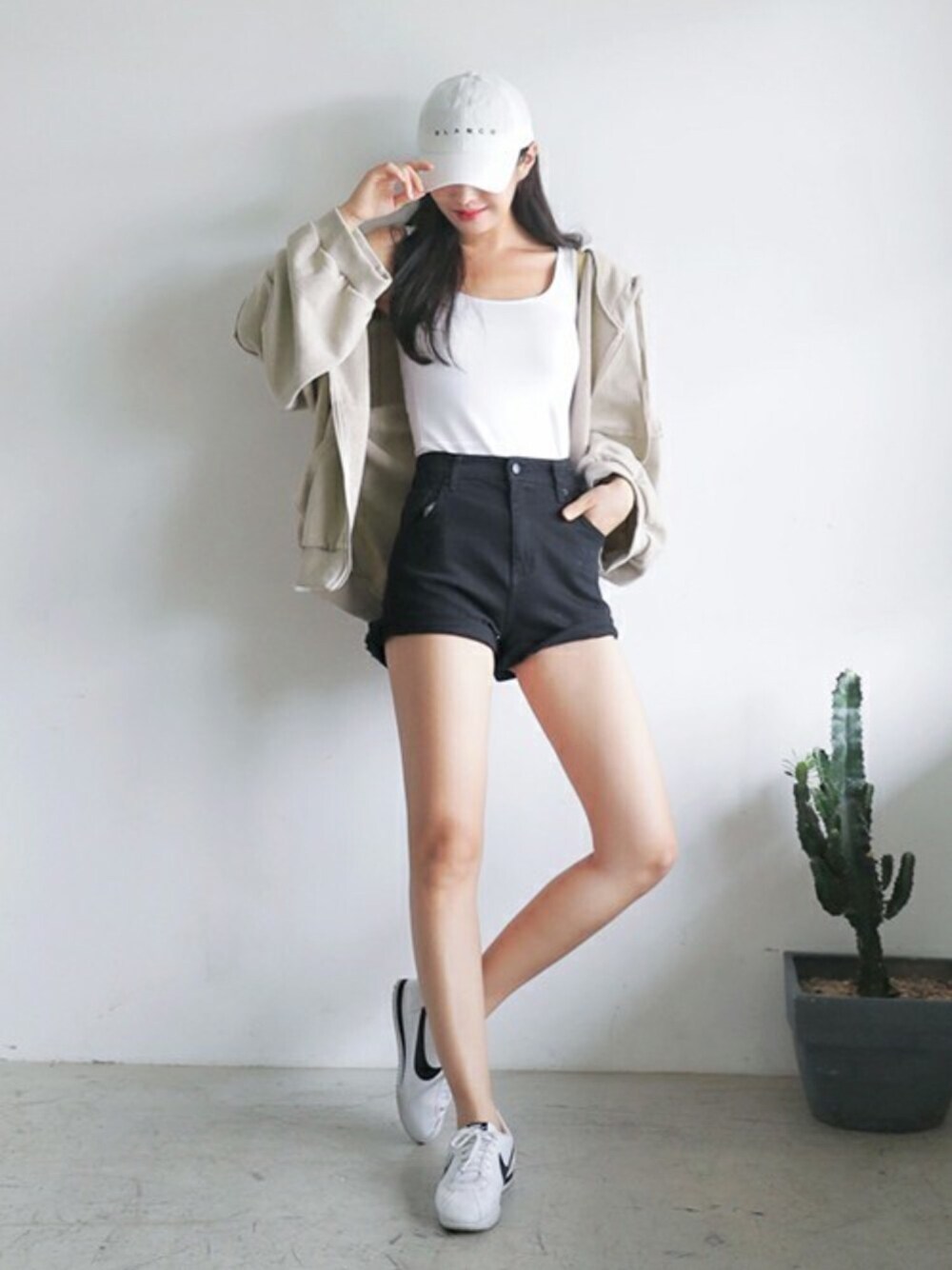ベージュ系のパーカー、ホワイト系のキャップを着用したレディースの夏コーディネートの1枚目の写真