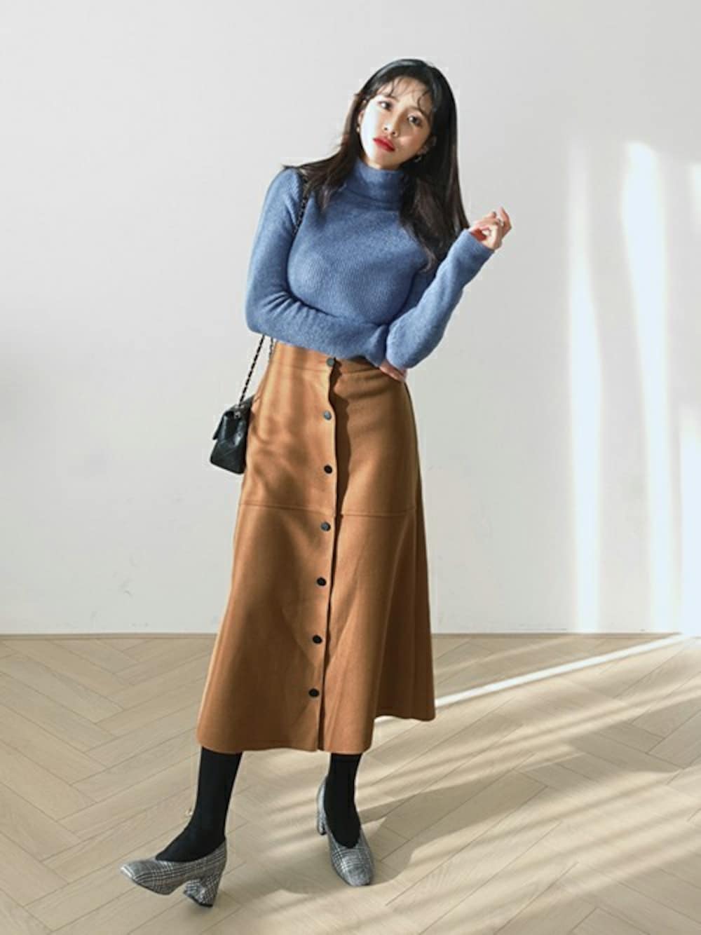 ブルー系のニット/セーター、ブラウン系のスカートを着用したレディースの冬コーディネートの1枚目の写真