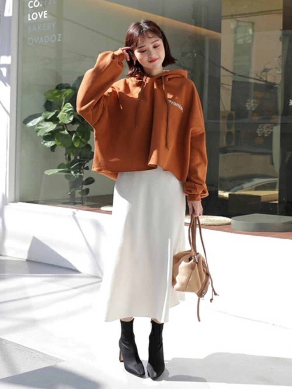 オレンジ系のスウェットを着用したレディースの秋コーディネートの1枚目の写真