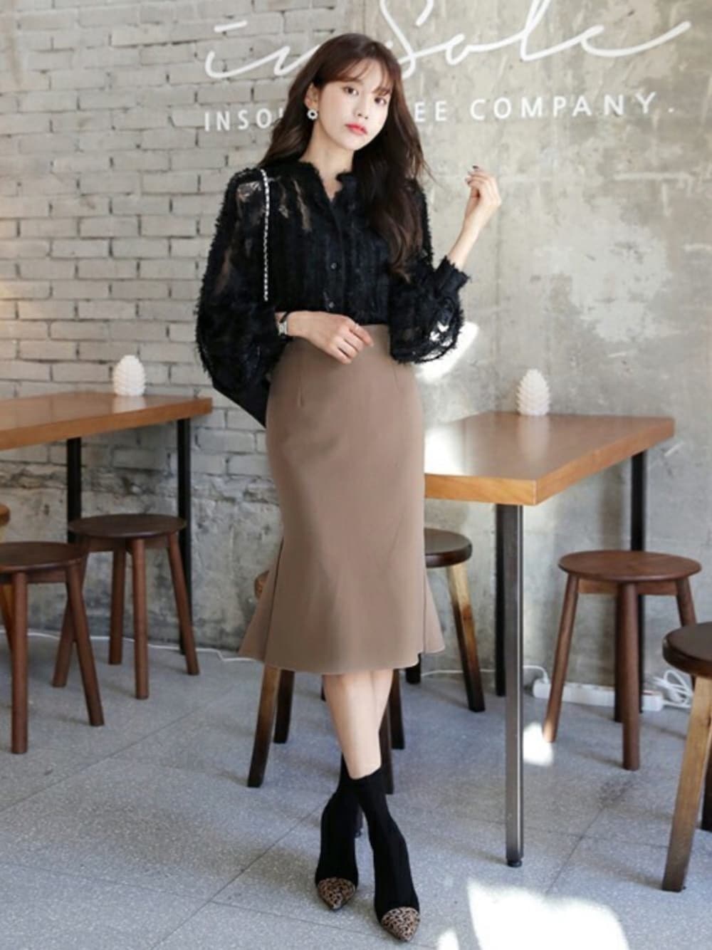 ブラック系のシャツ/ブラウス、ベージュ系のスカート、その他のブーツを着用したレディースの秋コーディネートの1枚目の写真