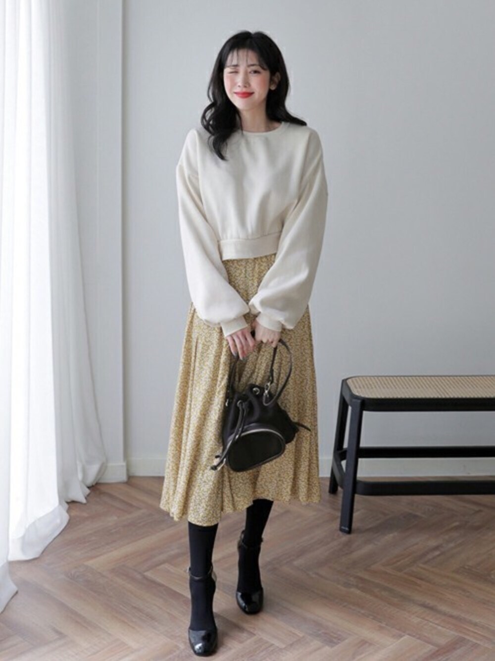 ホワイト系のスウェット、イエロー系のスカート、ブラック系のバックパック/リュックを着用したレディースの秋コーディネートの1枚目の写真