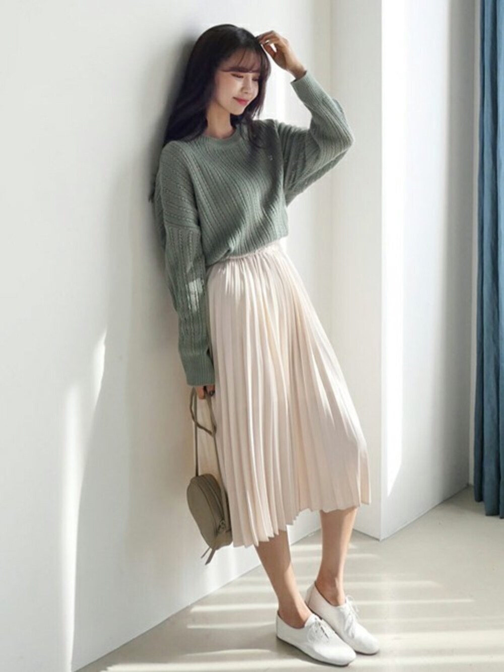 グリーン系のニット/セーター、ホワイト系のスカートを着用したレディースの冬コーディネートの1枚目の写真