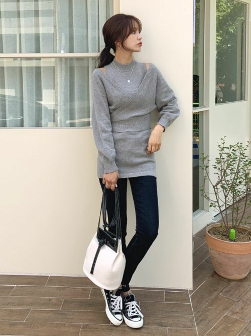 ブルー系のデニムパンツ、グレー系のアンサンブル、シルバー系のネックレスを着用したレディースの秋コーディネートの1枚目の写真