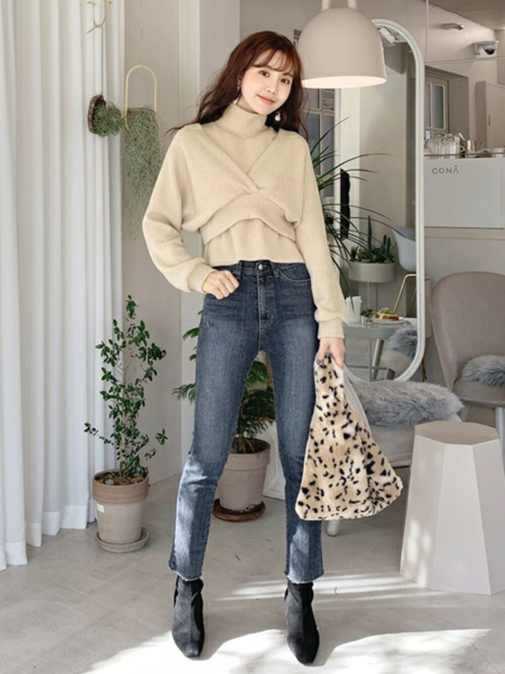 ベージュ系のニット/セーター、ブルー系のデニムパンツ、ベージュ系のハンドバッグを着用したレディースの冬コーディネートの1枚目の写真