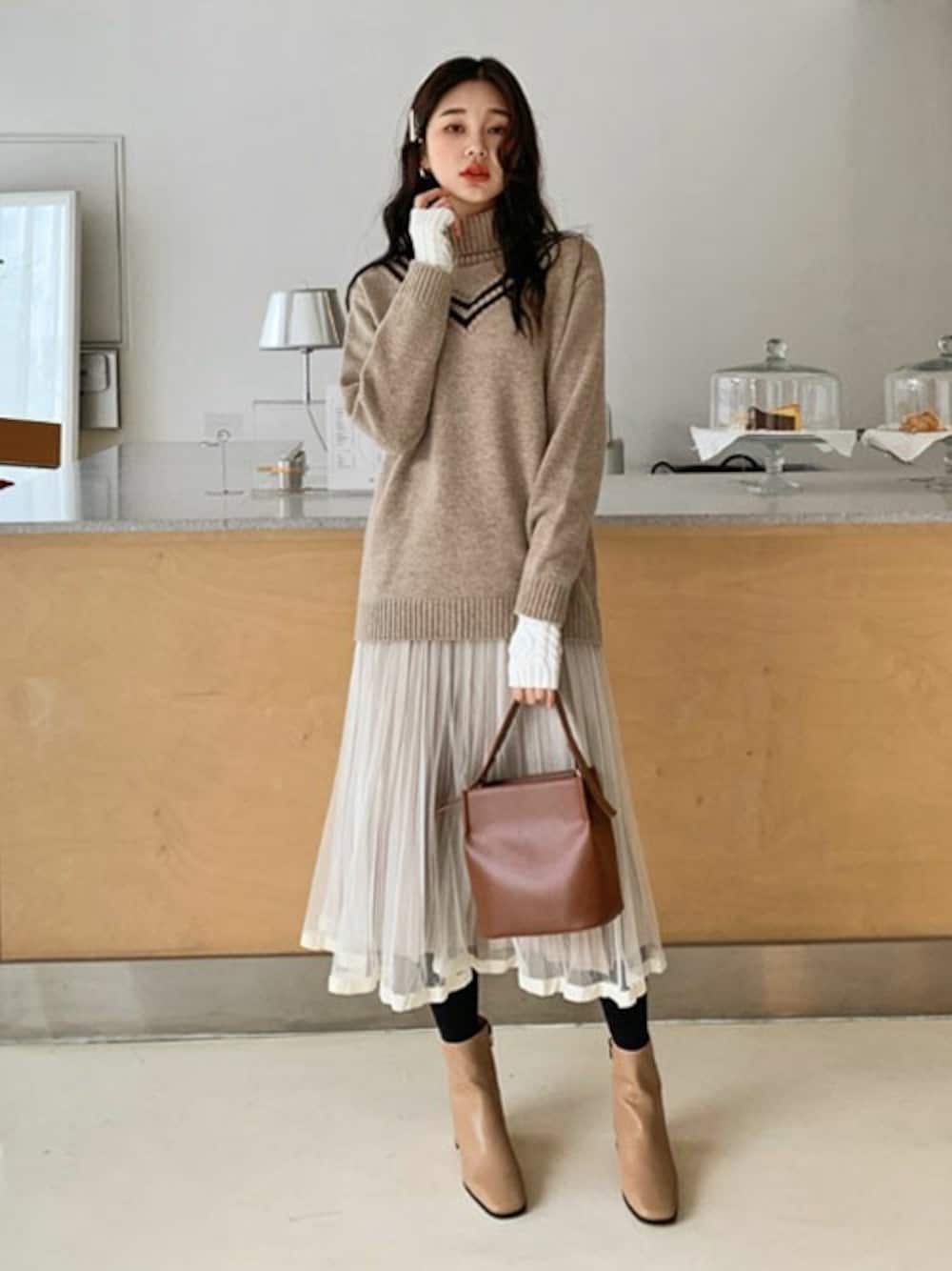 ベージュ系のニット/セーター、ブラウン系のショルダーバッグ、ベージュ系のブーツを着用したレディースの冬コーディネートの1枚目の写真