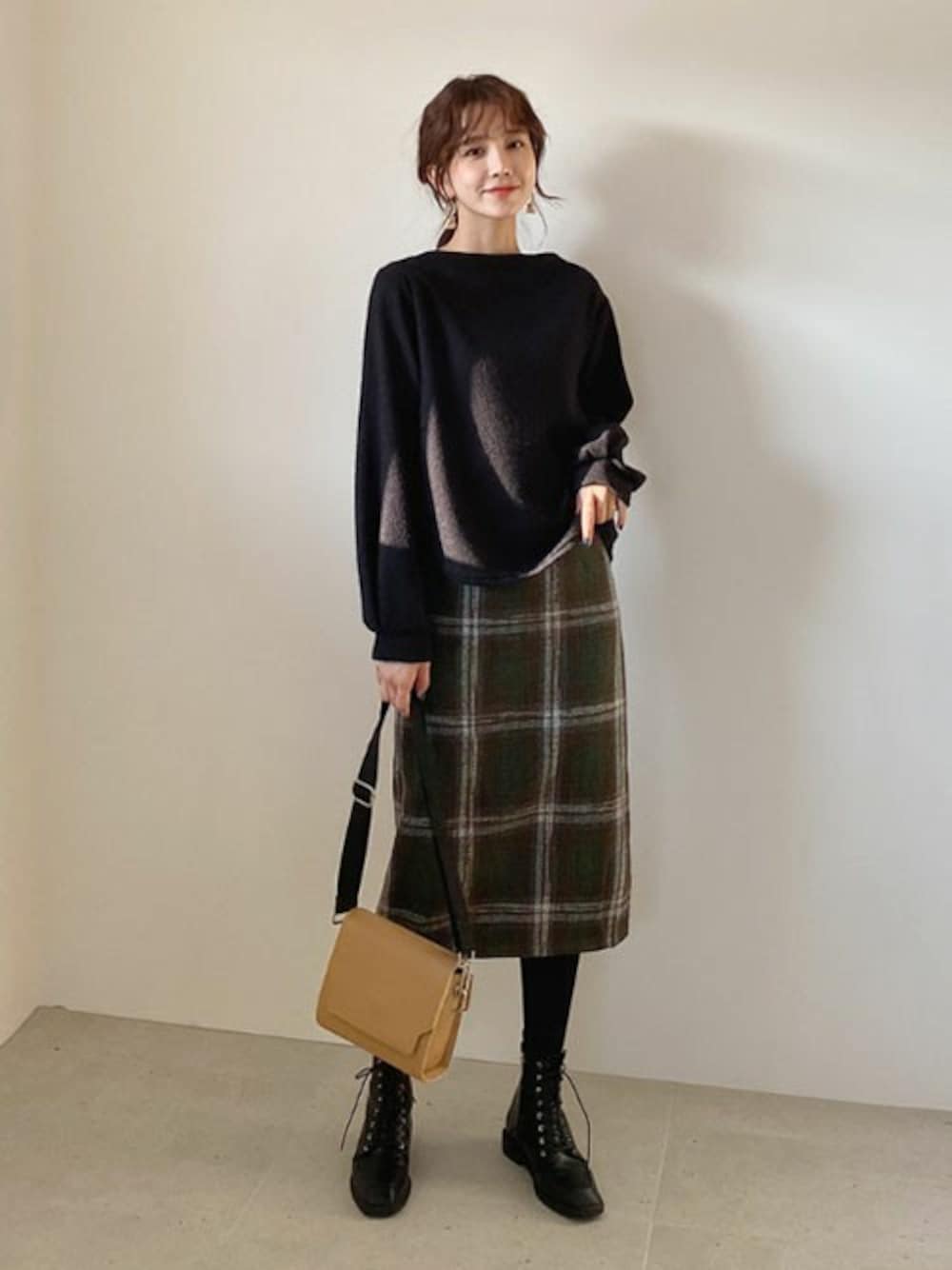 グリーン系のスカート、ブラック系のTシャツ/カットソー、ベージュ系のハンドバッグを着用したレディースの冬コーディネートの1枚目の写真