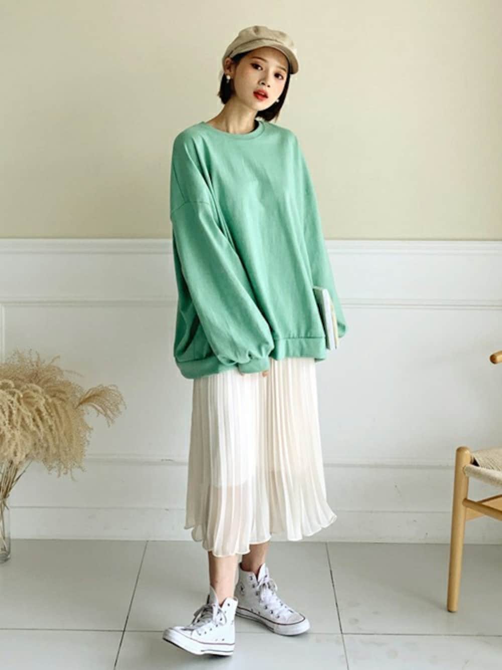 グリーン系のスウェット、ベージュ系のスカート、ゴールド系のピアス(両耳用)を着用したレディースの冬コーディネートの1枚目の写真