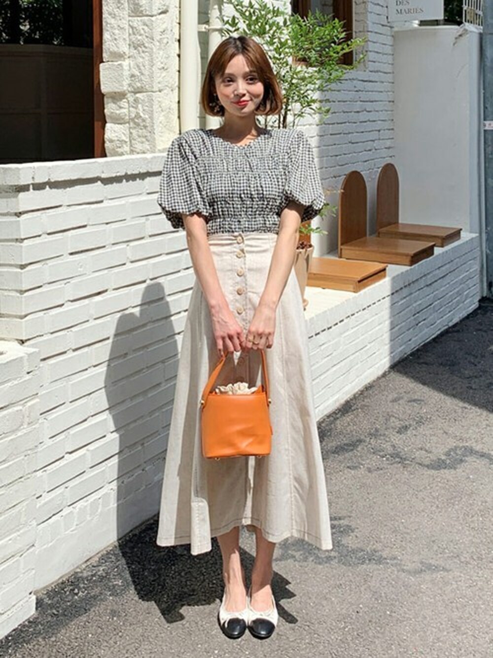 ホワイト系のスカート、オレンジ系のハンドバッグ、その他のTシャツ/カットソーを着用したレディースの夏コーディネートの1枚目の写真