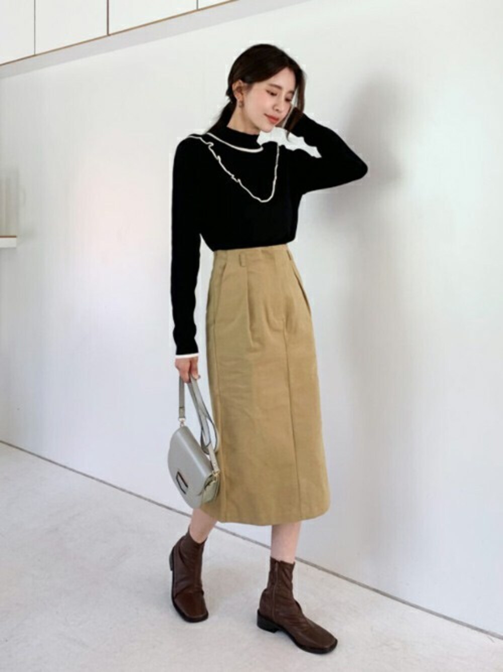 ブラック系のニット/セーター、ベージュ系のスカート、その他のTシャツ/カットソーを着用したレディースの秋コーディネートの1枚目の写真