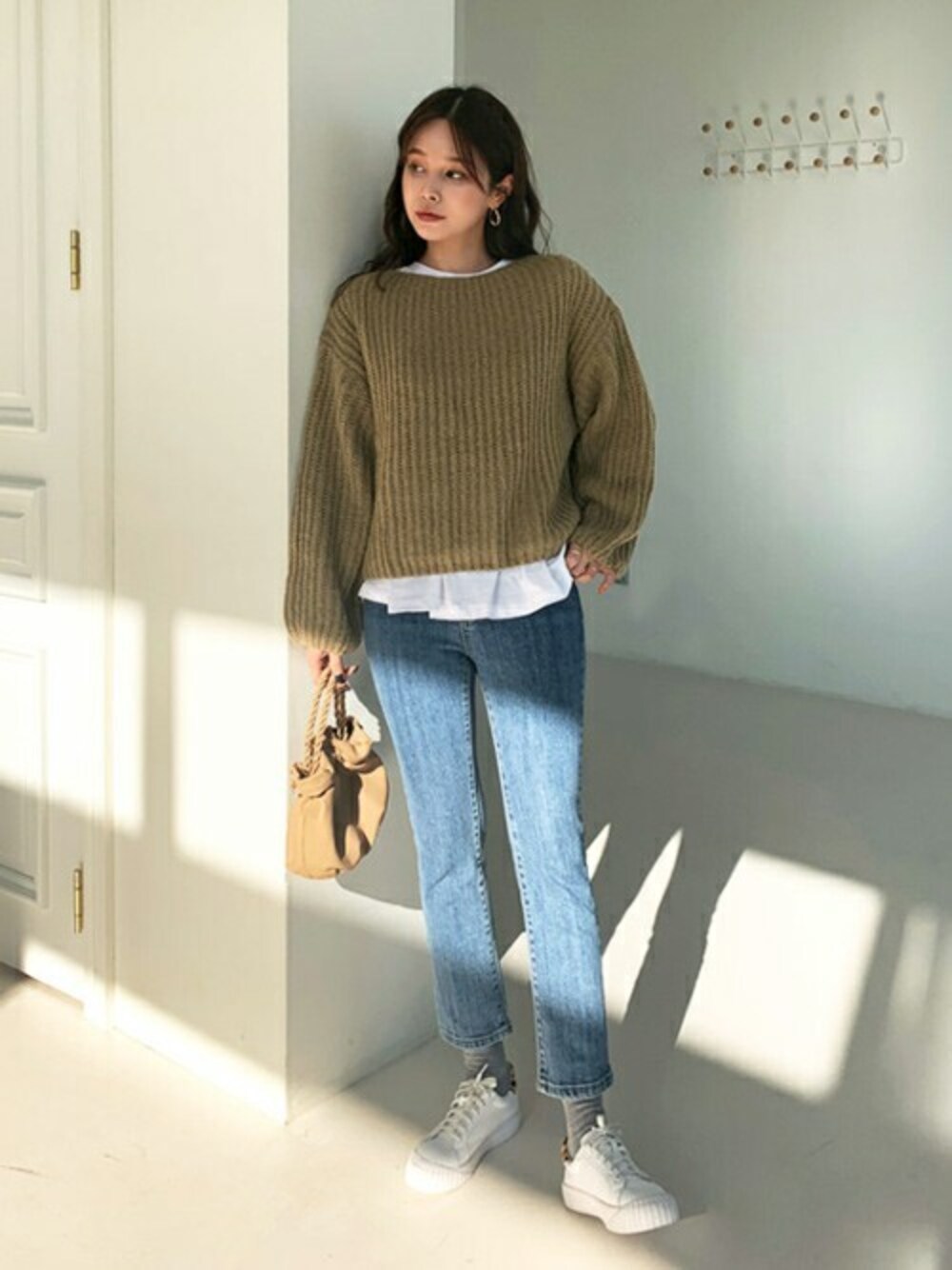 ベージュ系のニット/セーター、ブルー系のデニムパンツ、ホワイト系のその他を着用したレディースの秋コーディネートの1枚目の写真