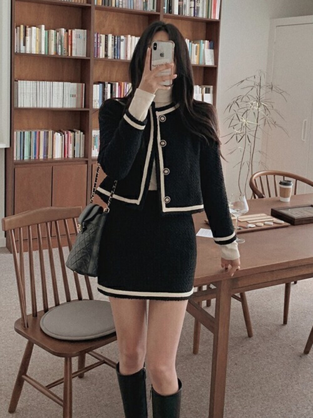 ブラック系のノーカラーコート、ブラック系のスカートを着用したレディースの冬コーディネートの1枚目の写真