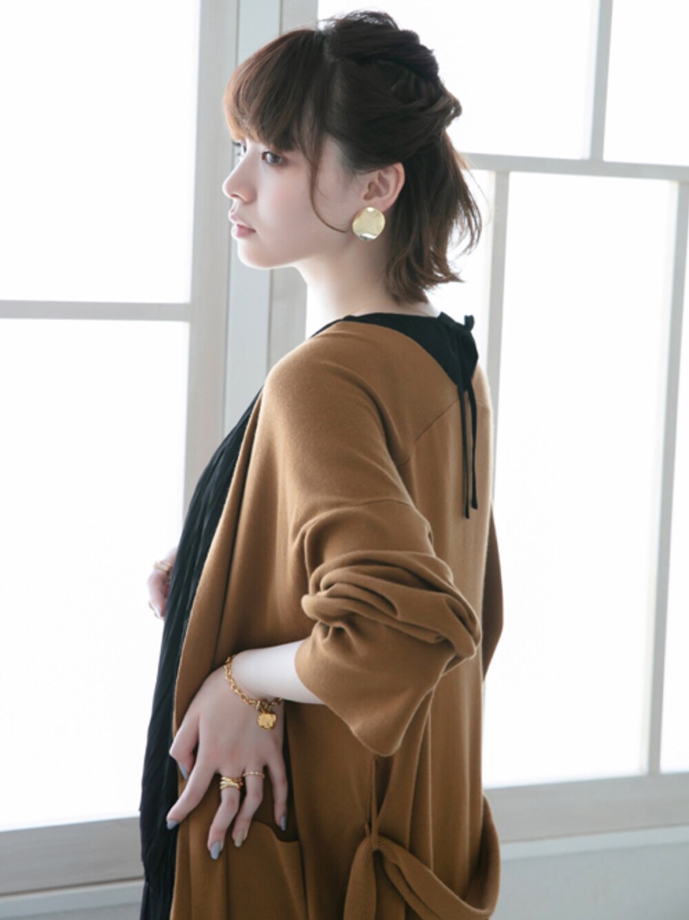 ブラウン系のカーディガン/ボレロ、ブラック系のワンピース、ゴールド系のイヤリングを着用したレディースの秋コーディネートの1枚目の写真