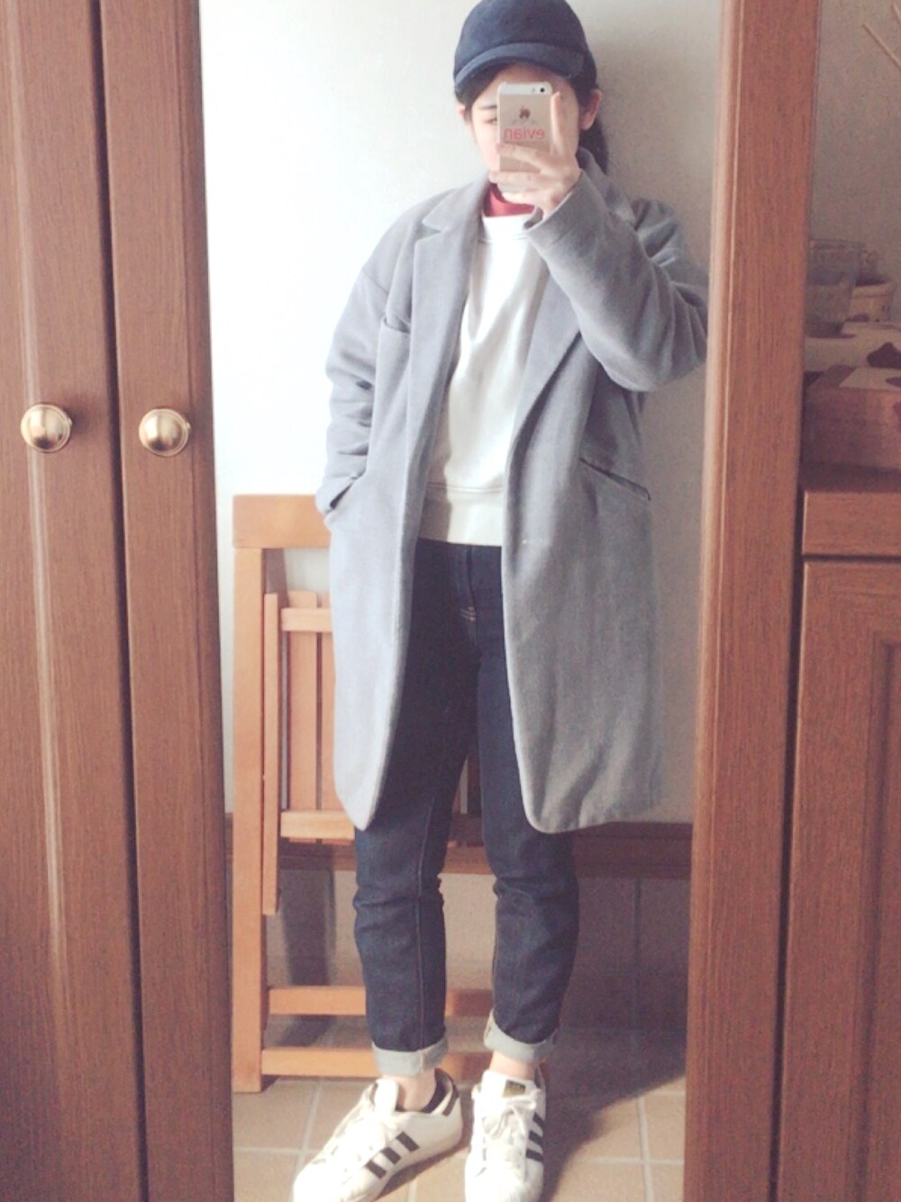 グレー系のチェスターコート、ホワイト系のスウェット、オレンジ系のシャツ/ブラウスを着用したレディースの春コーディネートの1枚目の写真