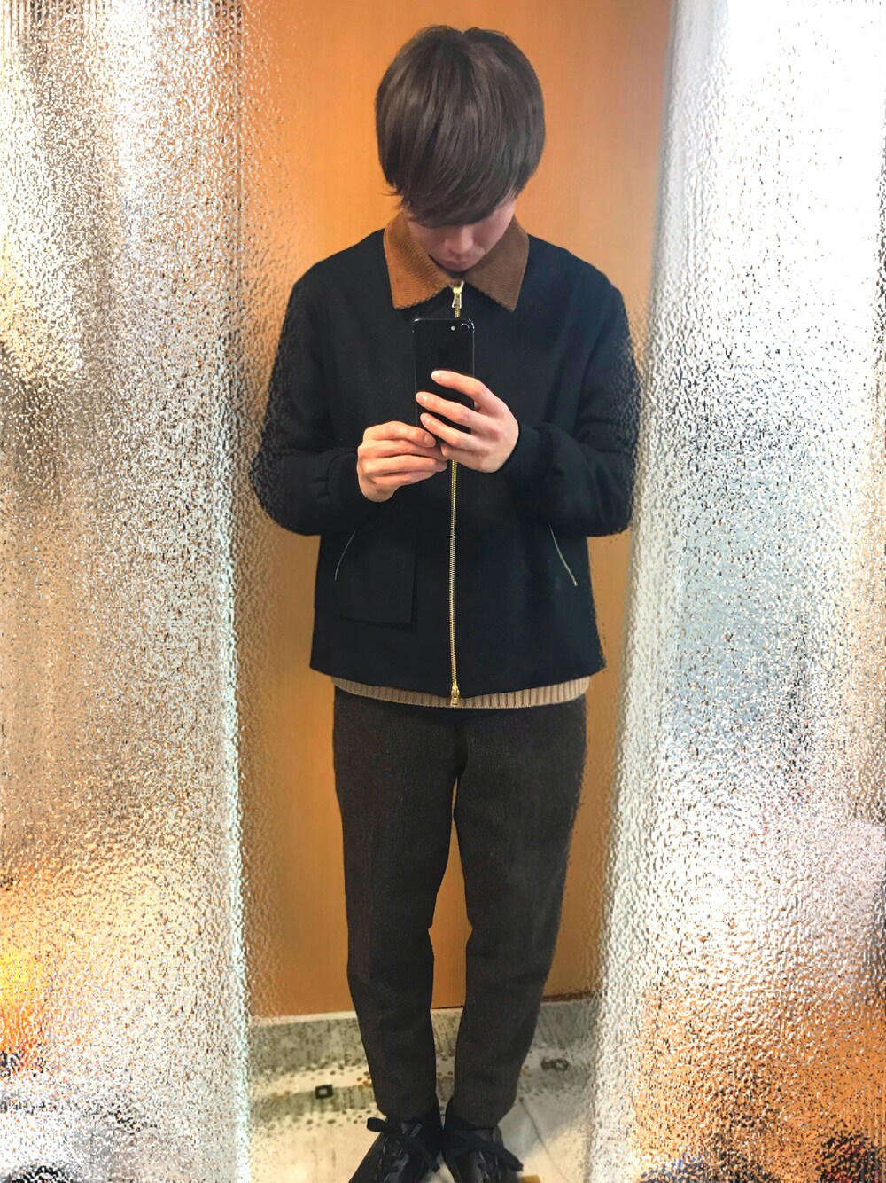 ブラック系のブルゾン、ベージュ系のニット/セーター、ブラウン系のパンツを着用したメンズの冬コーディネートの1枚目の写真