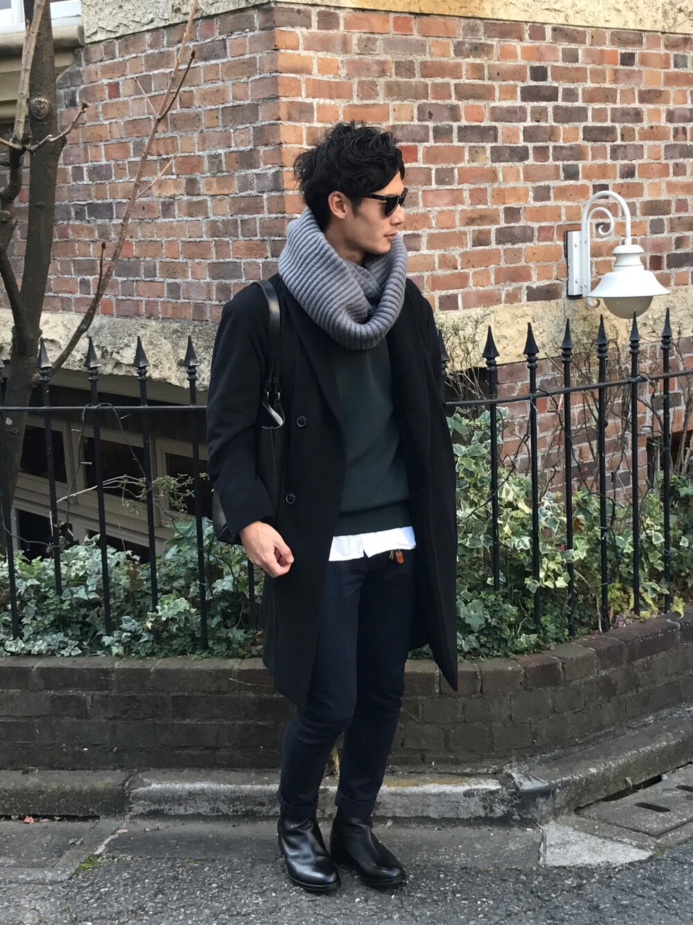 ブラック系のチェスターコート、グリーン系のニット/セーター、ホワイト系のシャツ/ブラウスを着用したメンズの冬コーディネートの1枚目の写真