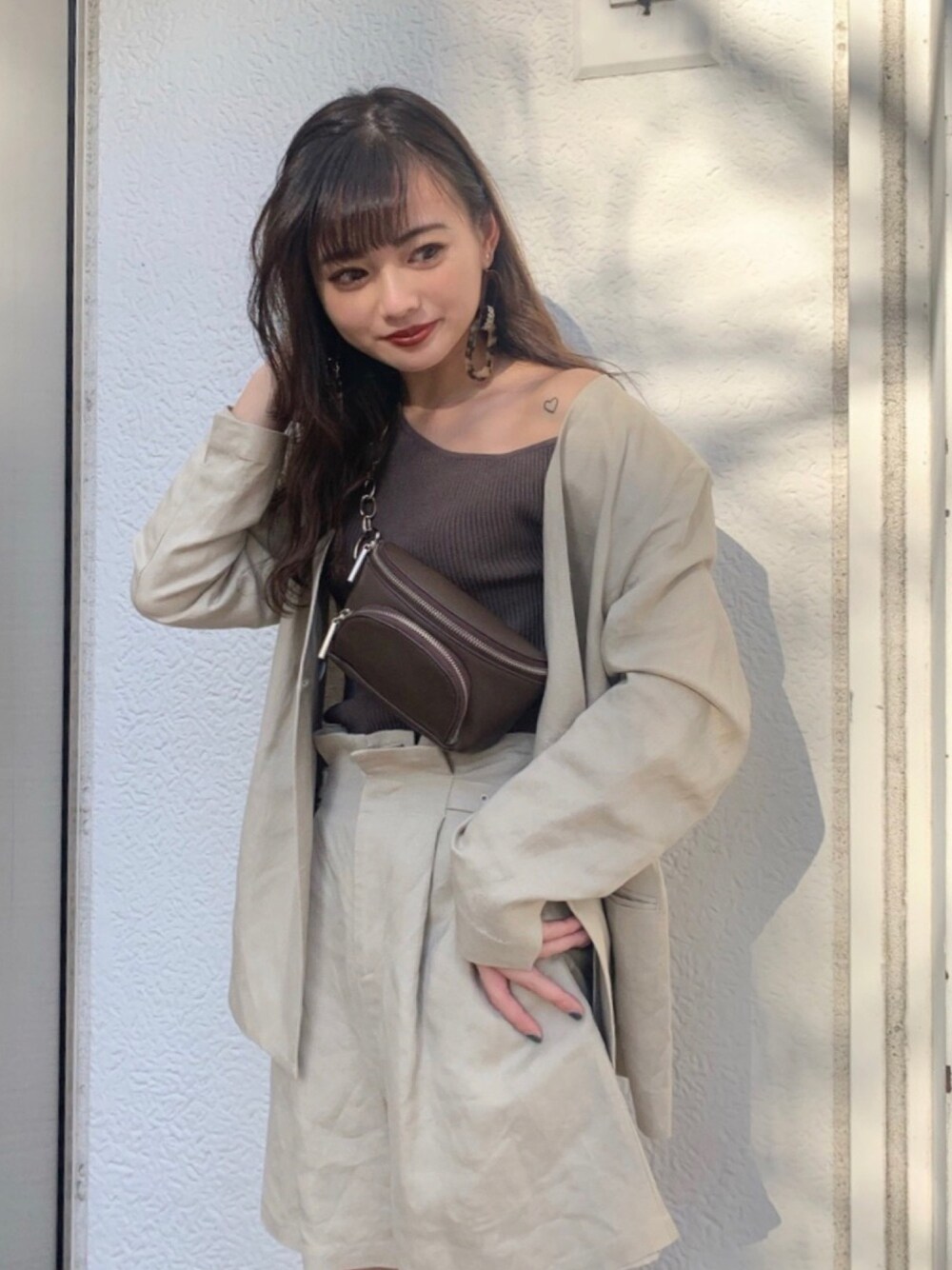 ブラウン系のニット/セーター、ブラウン系のボディバッグ/ウエストポーチを着用したレディースの春コーディネートの1枚目の写真