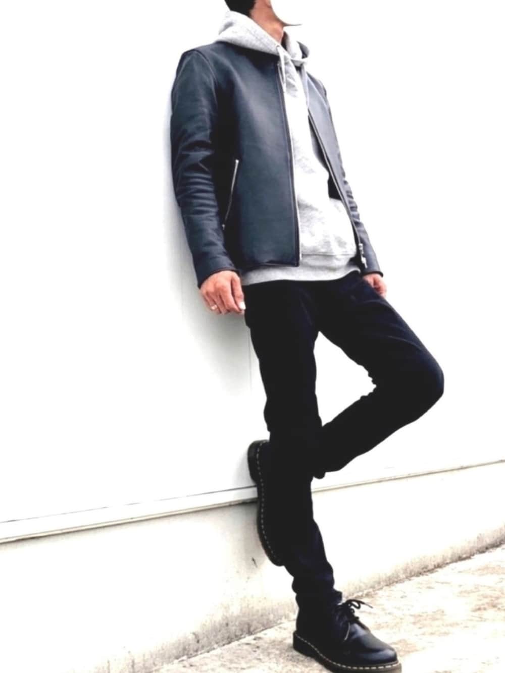 ブラック系のライダースジャケット、グレー系のパーカー、ブラック系のその他パンツを着用したメンズの冬コーディネートの1枚目の写真
