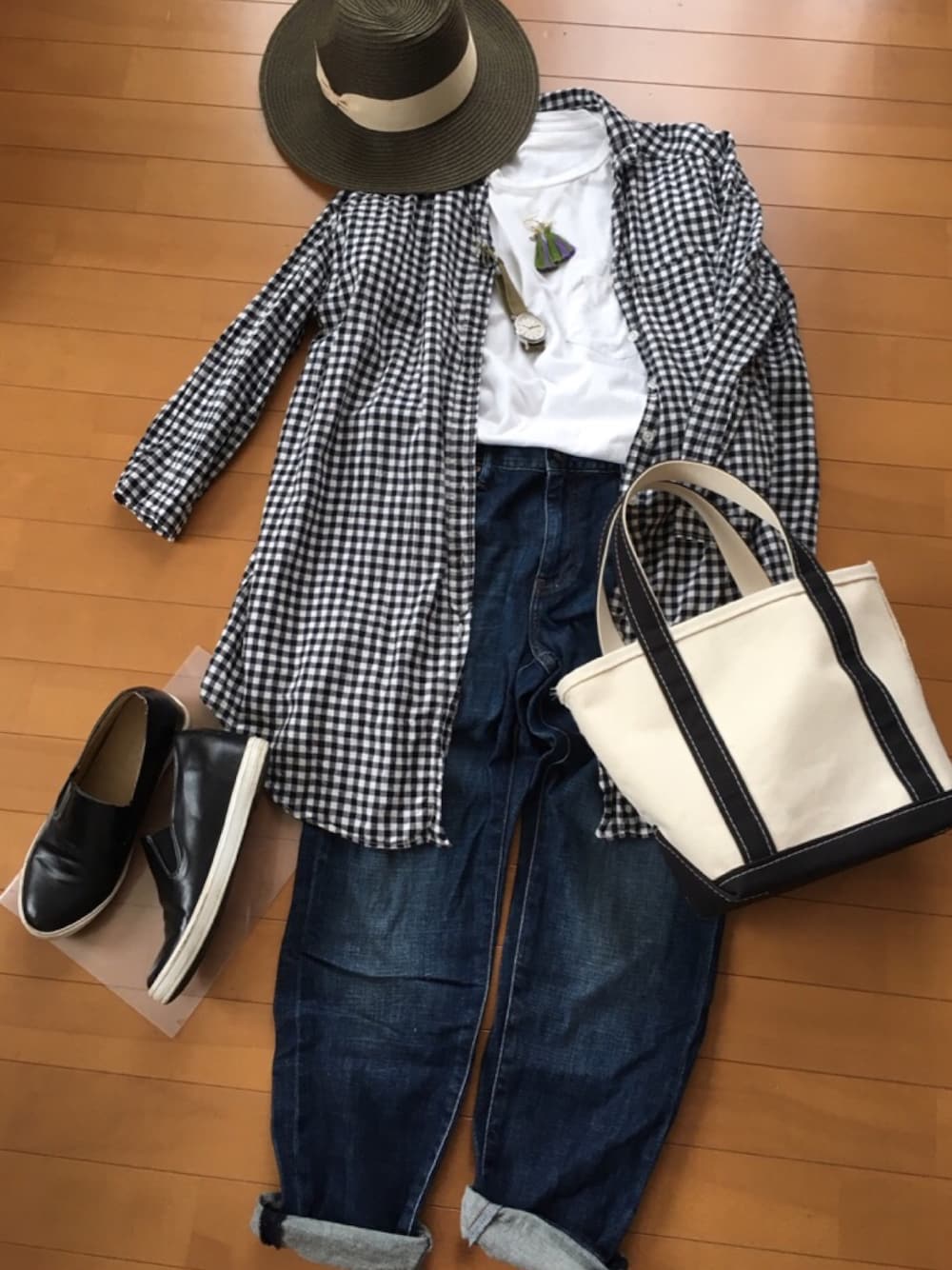 ブルー系のデニムパンツ、ホワイト系のトートバッグ、ブラック系のシャツ/ブラウスを着用したレディースの夏コーディネートの1枚目の写真