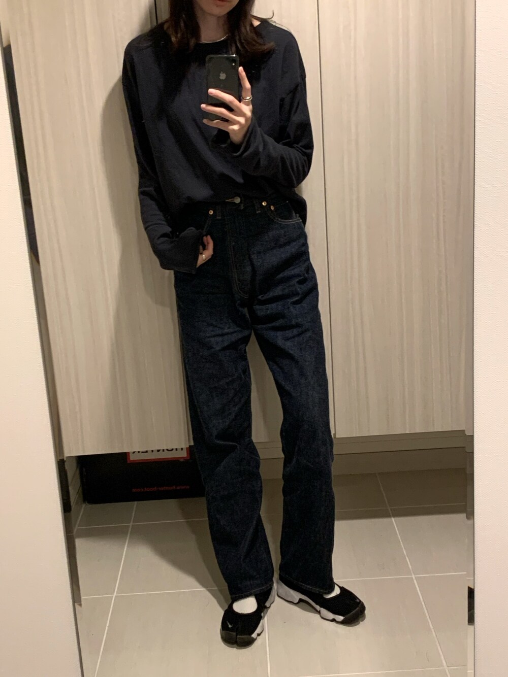 ブルー系のデニムパンツ、ブラック系のスニーカー、ブラック系のTシャツ/カットソーを着用したレディースの春コーディネートの1枚目の写真