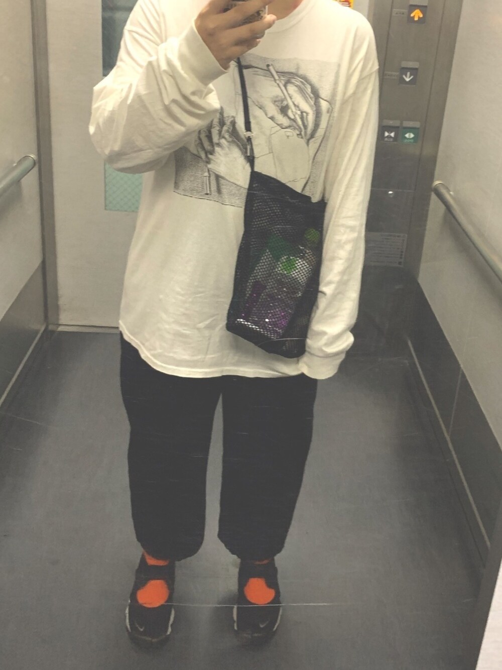 ブラック系のバッグ、ホワイト系のTシャツ/カットソー、ブラック系のスラックスを着用したレディースの秋コーディネートの1枚目の写真
