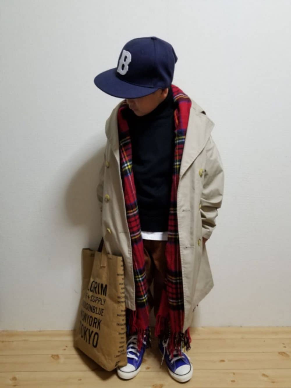ベージュ系のトレンチコート、ブラック系のニット/セーター、ホワイト系のTシャツ/カットソーを着用したキッズの冬コーディネートの1枚目の写真