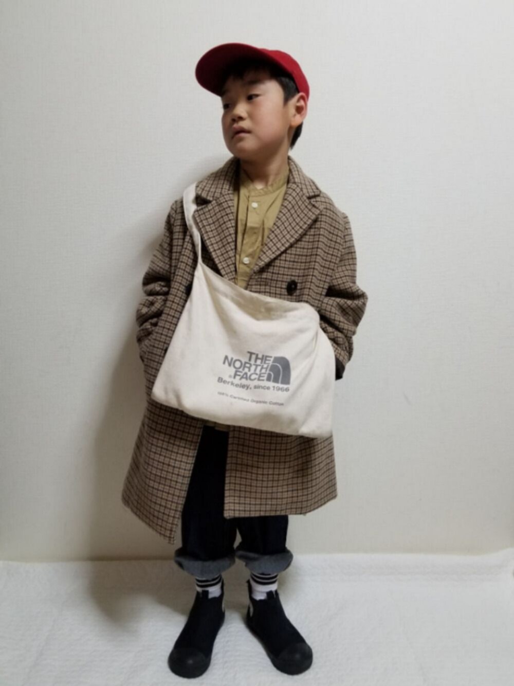 ベージュ系のチェスターコート、ベージュ系のシャツ/ブラウス、ブラック系のスニーカーを着用したキッズの冬コーディネートの1枚目の写真