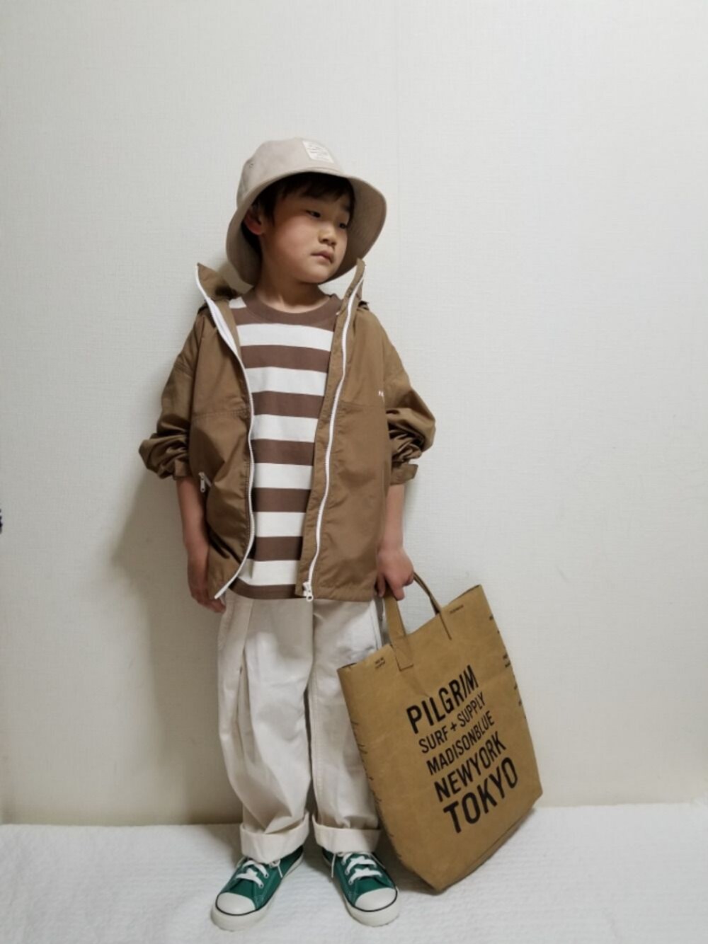 ベージュ系のブルゾン、ブラウン系のTシャツ/カットソー、ホワイト系のパンツを着用したキッズの春コーディネートの1枚目の写真