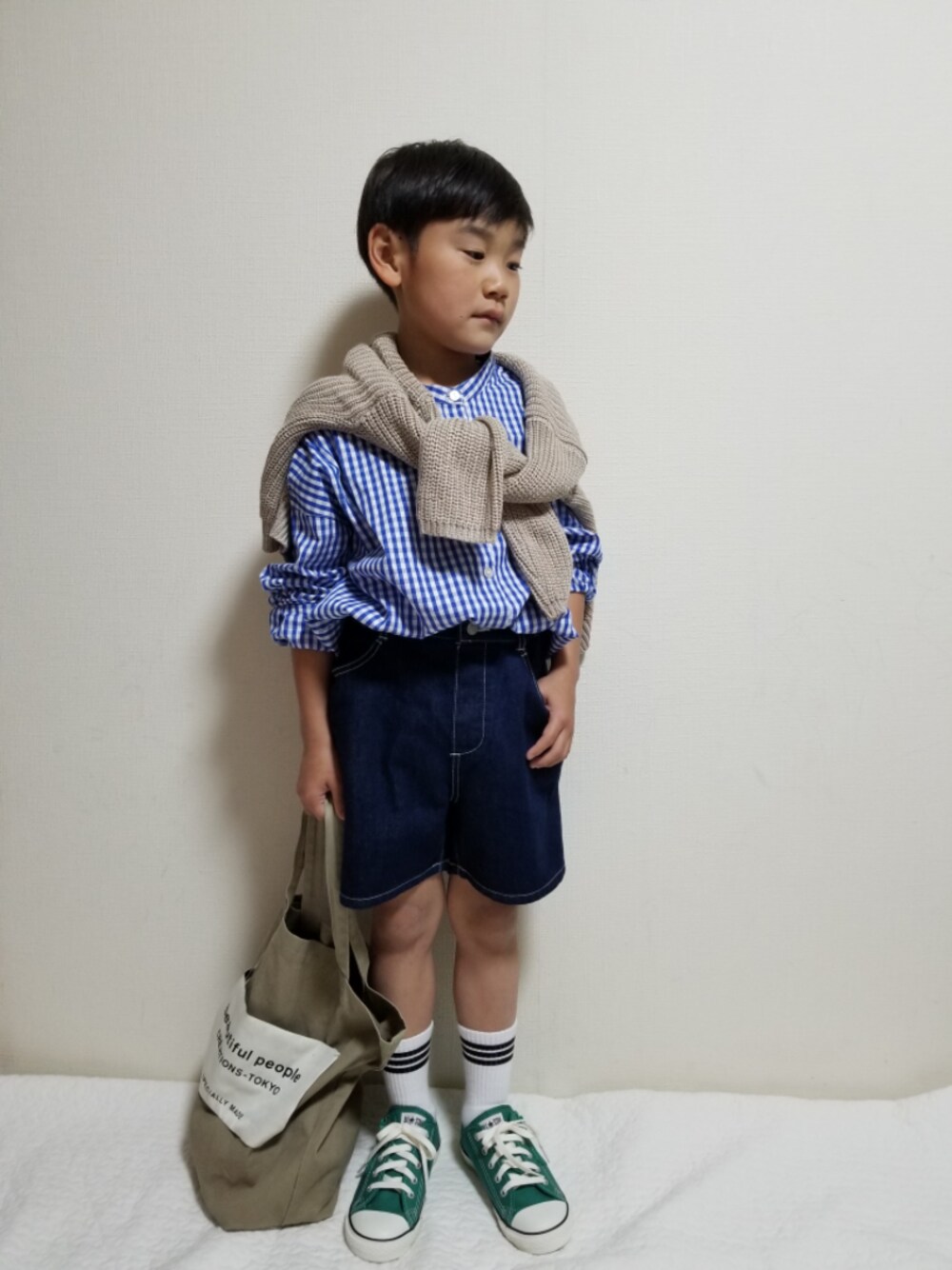 ベージュ系のトートバッグ、グリーン系のスニーカー、ブルー系のデニムパンツを着用したキッズの春コーディネートの1枚目の写真