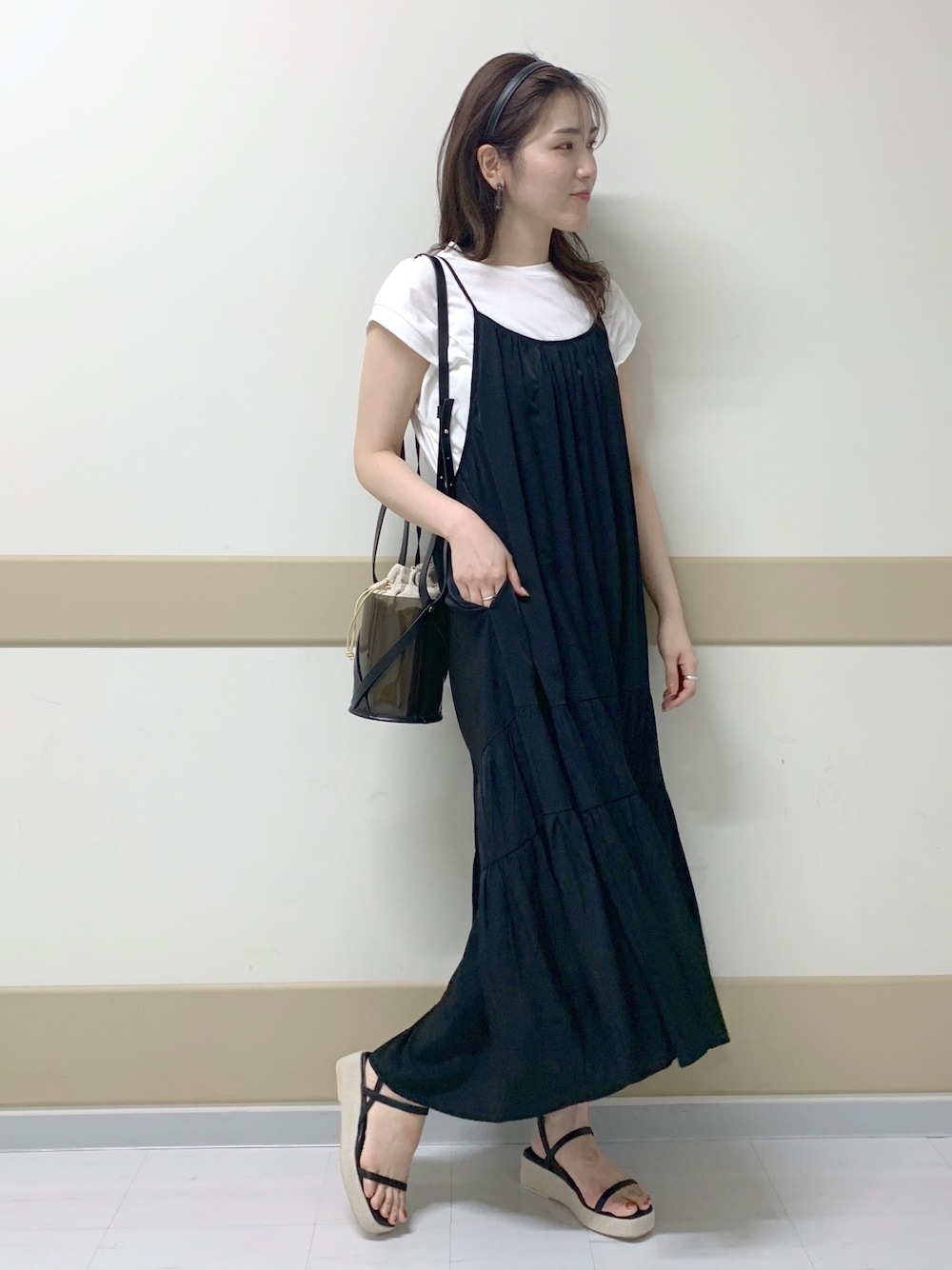 ブラック系のワンピース、ホワイト系のTシャツ/カットソー、ブラック系のサンダルを着用したレディースの春コーディネートの1枚目の写真