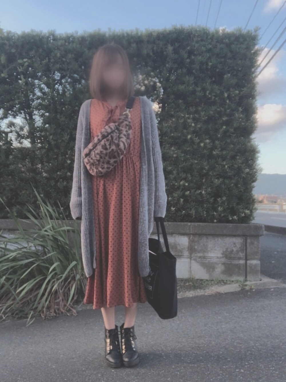 グレー系のカーディガン/ボレロ、オレンジ系のワンピース、ブラック系のブーツを着用したレディースの秋コーディネートの1枚目の写真