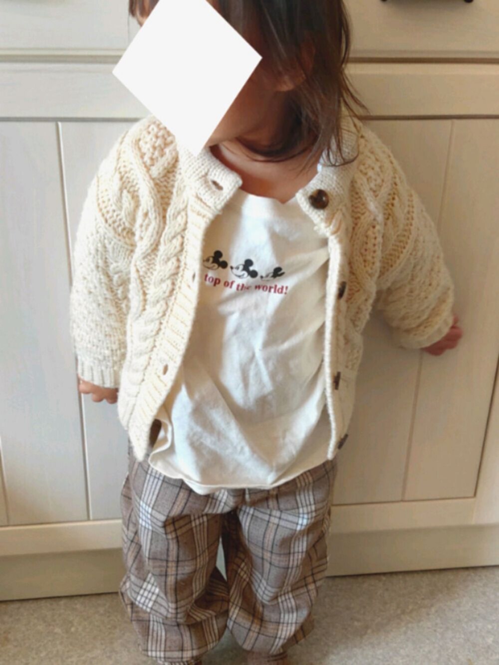 ベージュ系のパンツ、ホワイト系のTシャツ/カットソー、ホワイト系のカーディガン/ボレロを着用したキッズの冬コーディネートの1枚目の写真