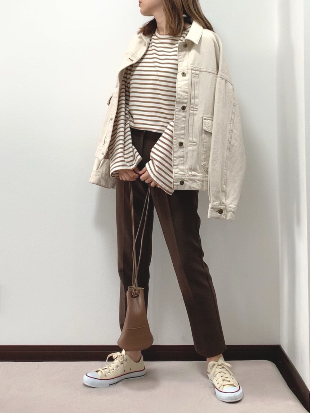 ホワイト系のデニムジャケット、ブラウン系のTシャツ/カットソー、ブラウン系のスラックスを着用したレディースの春コーディネートの1枚目の写真