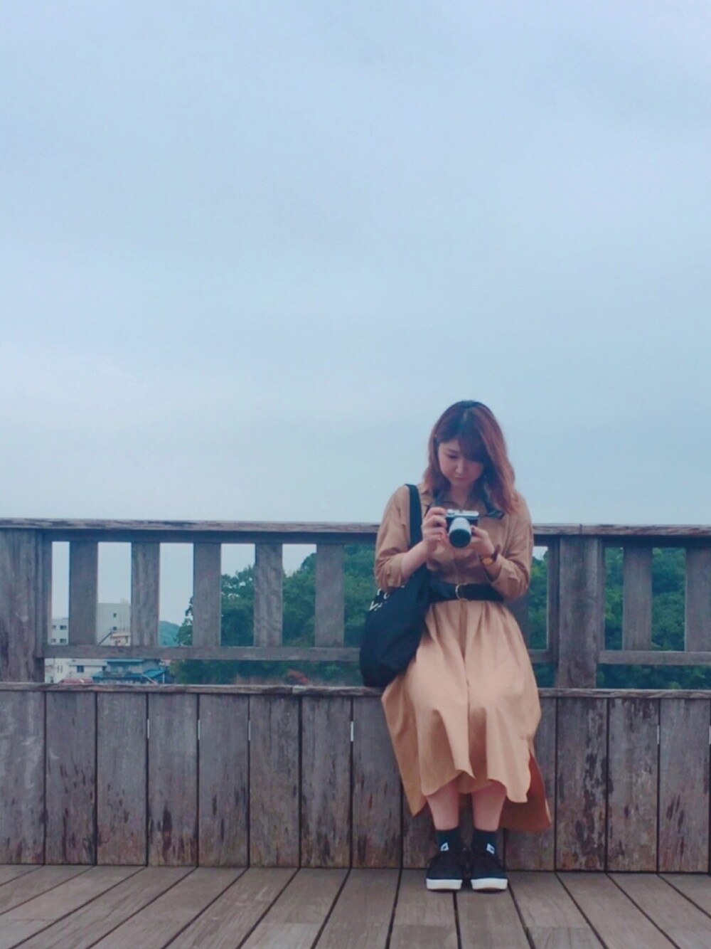 ベージュ系のシャツワンピース、ブラック系のベルト、グリーン系のイヤリングを着用したレディースの秋コーディネートの1枚目の写真