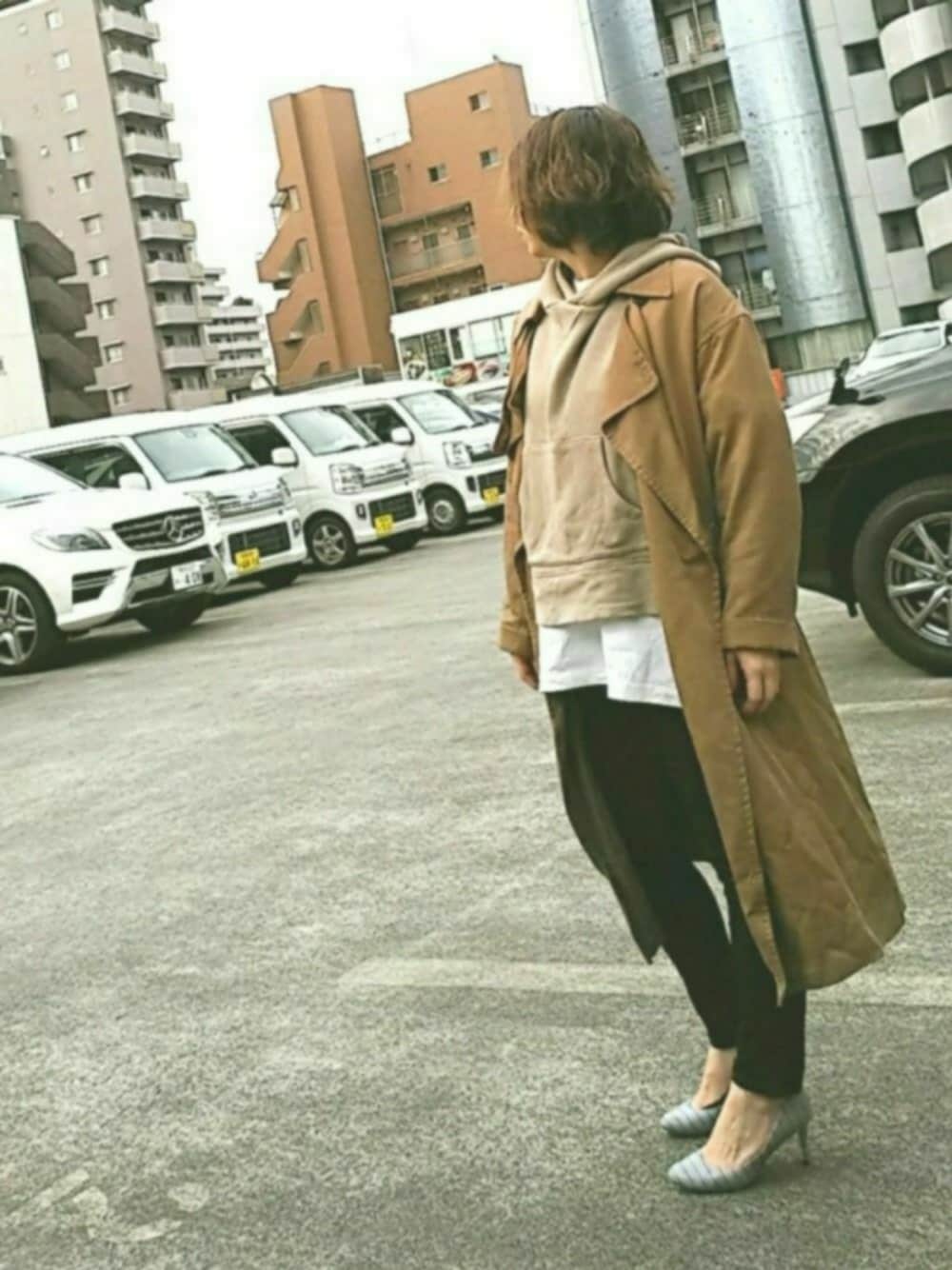 ブラウン系のパーカー、イエロー系のトレンチコート、ホワイト系のTシャツ/カットソーを着用したレディースの春コーディネートの1枚目の写真