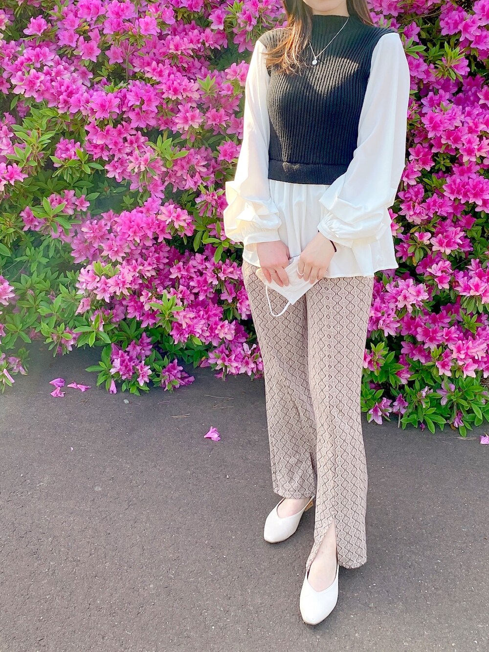 ブラック系のトップス、ブラウン系のパンツ、ホワイト系のシューズを着用したレディースの春コーディネートの1枚目の写真