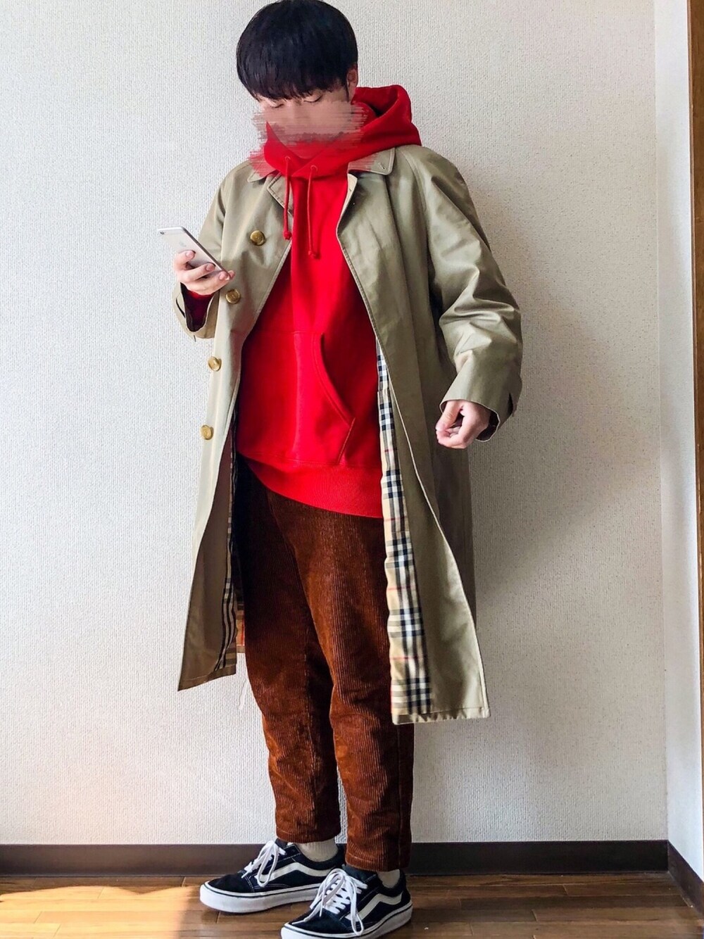 ベージュ系のステンカラーコート、レッド系のパーカー、ブラウン系のパンツを着用したメンズの秋コーディネートの1枚目の写真