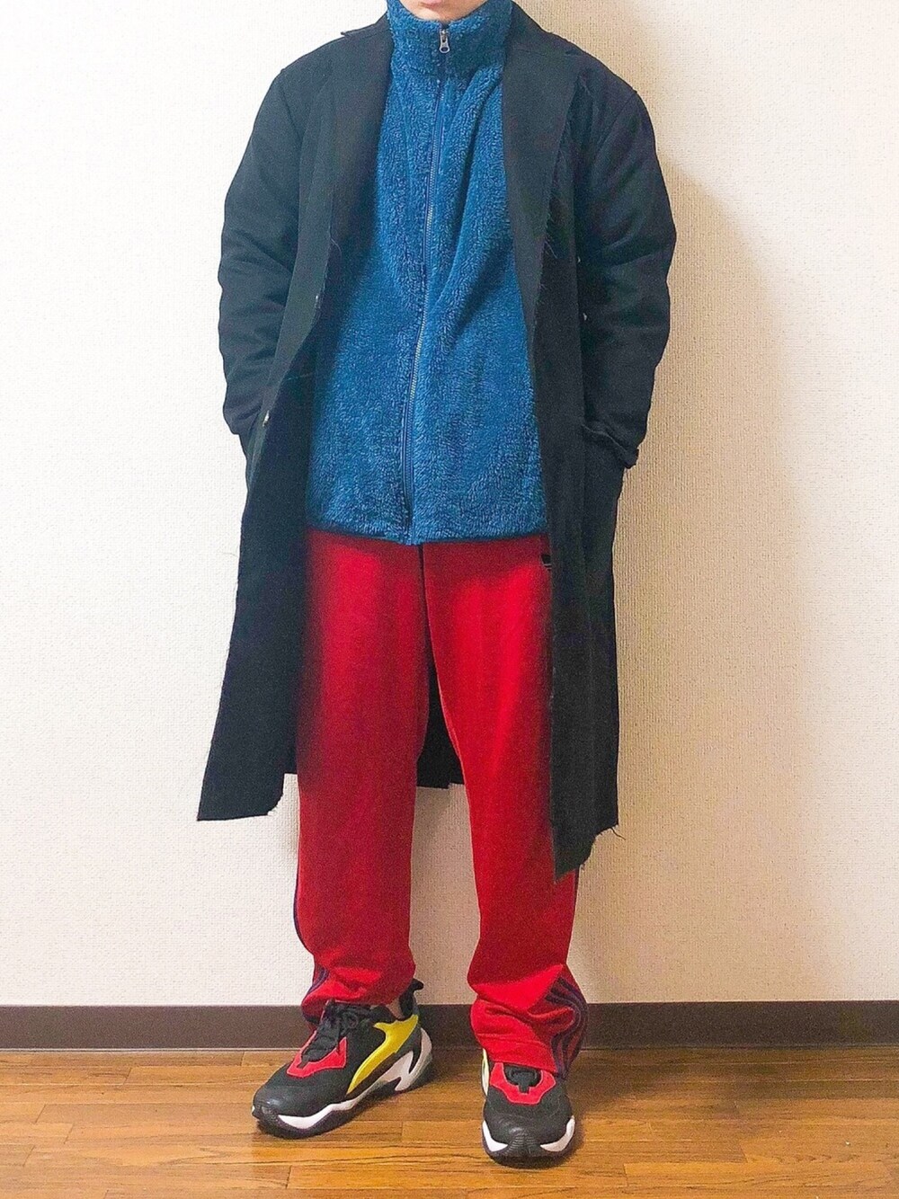 ブラック系のチェスターコート、ブルー系のその他アウター、レッド系のパンツを着用したメンズの冬コーディネートの1枚目の写真