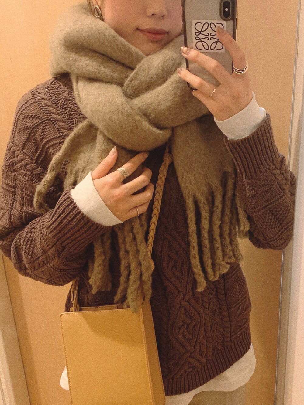 ブラウン系のニット/セーター、ベージュ系のショルダーバッグ、ベージュ系のマフラーを着用したレディースの冬コーディネートの1枚目の写真