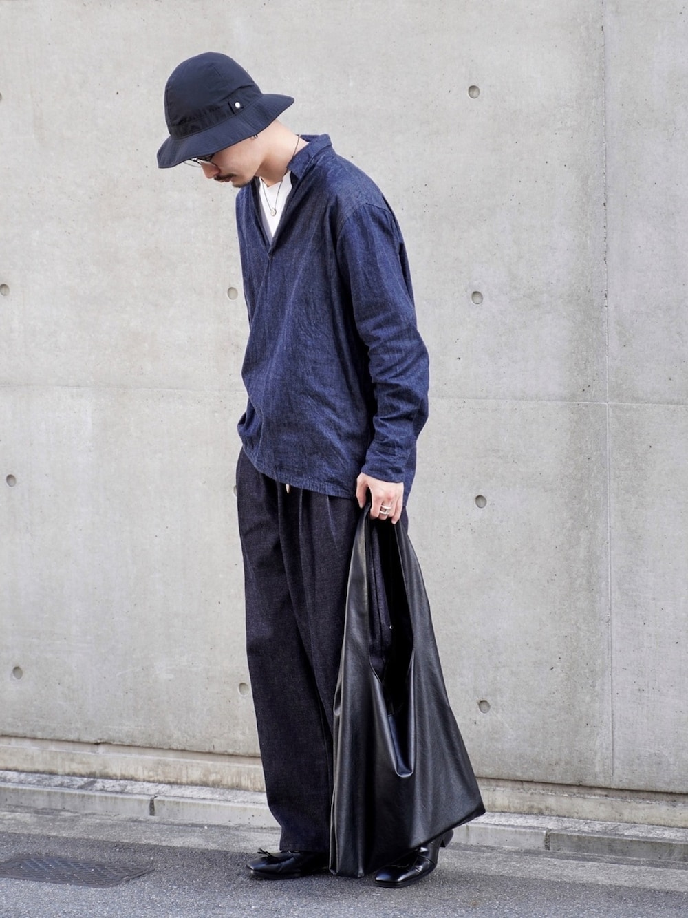 ブラック系のトートバッグ、ブルー系のデニムパンツ、ブルー系のトップスを着用したメンズの秋コーディネートの1枚目の写真