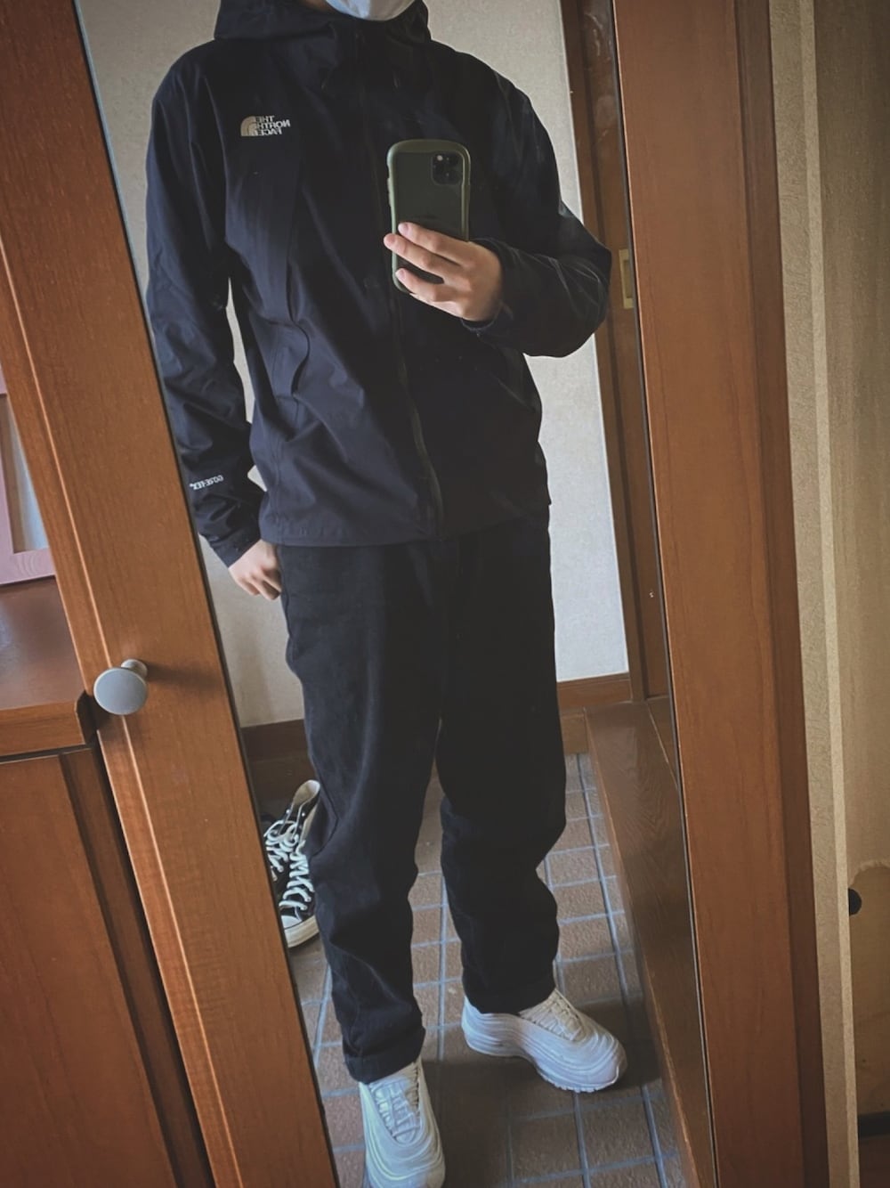 ホワイト系のスニーカー、ブラック系のマウンテンパーカー、ブラック系のパンツを着用したメンズの春コーディネートの1枚目の写真