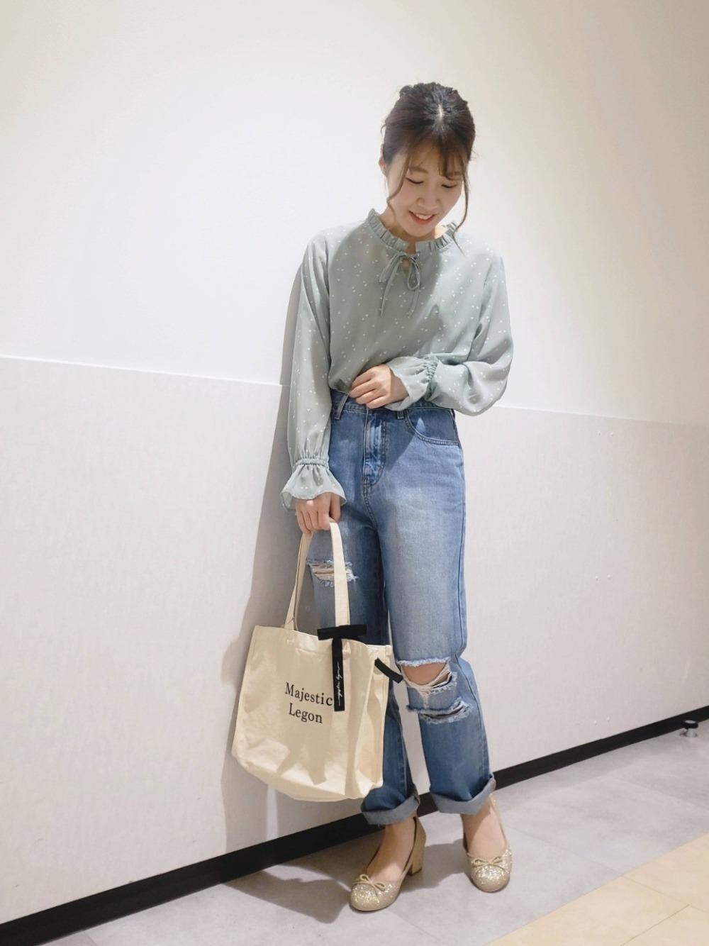 ホワイト系のトートバッグ、ゴールド系のパンプス、グリーン系のシャツ/ブラウスを着用したレディースの春コーディネートの1枚目の写真