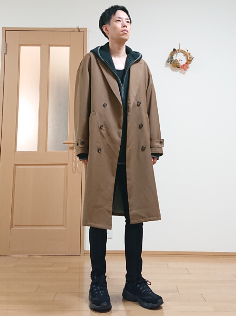 ブラウン系のチェスターコート、ブラック系のパーカー、ブラック系のスニーカーを着用したメンズの秋コーディネートの1枚目の写真