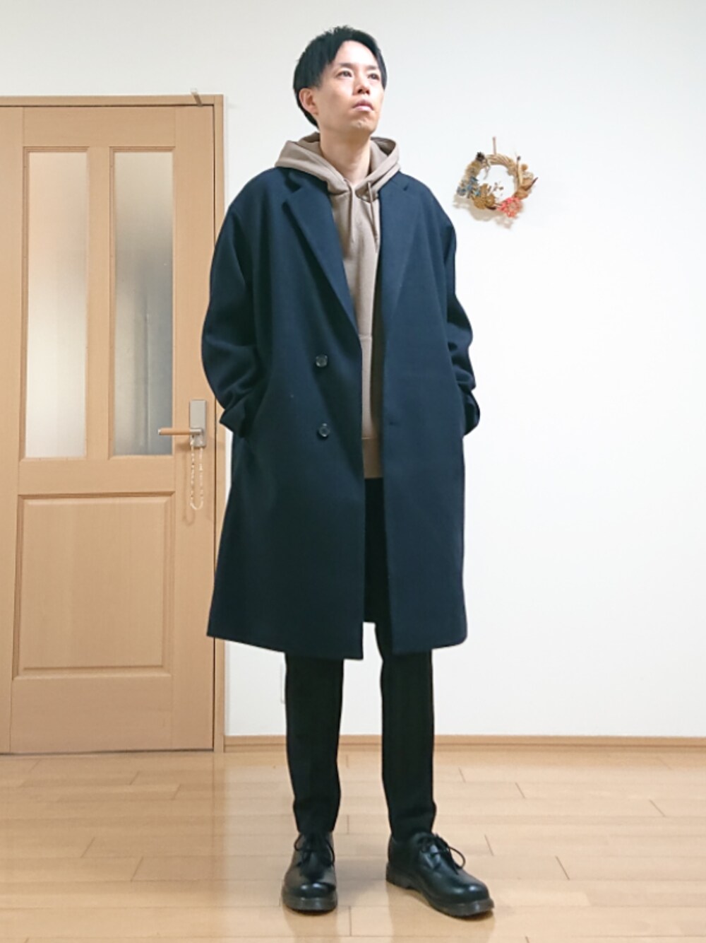 ブルー系のチェスターコート、ベージュ系のスウェット、ブラック系のスラックスを着用したメンズの冬コーディネートの1枚目の写真