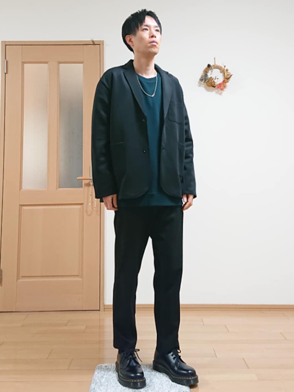 ブラック系のスラックス、ブラック系のテーラードジャケット、グリーン系のスウェットを着用したメンズの春コーディネートの1枚目の写真