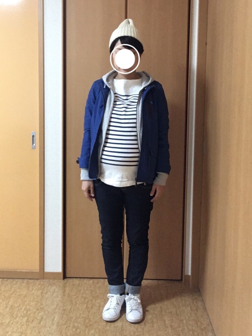 グレー系のパーカー、ホワイト系のスニーカー、ブルー系のマウンテンパーカーを着用したレディースの冬コーディネートの1枚目の写真