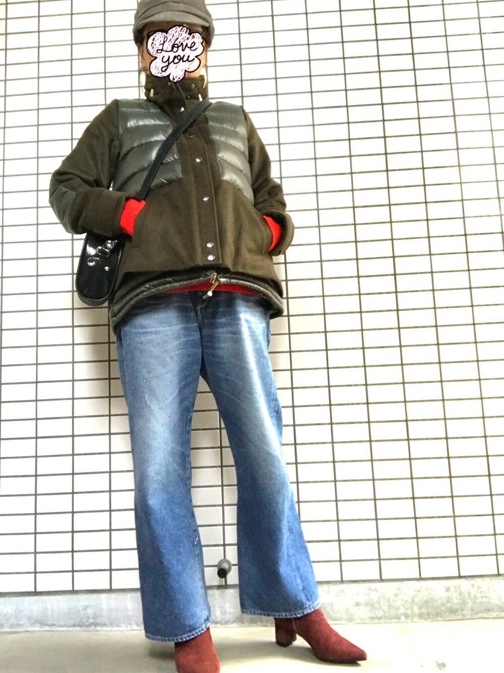 グリーン系のダウンジャケット/コート、レッド系のニット/セーター、ブラック系のショルダーバッグを着用したレディースの冬コーディネートの1枚目の写真